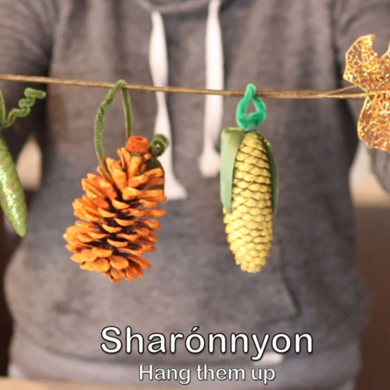 Photo of person holding string with acorn and corn craft